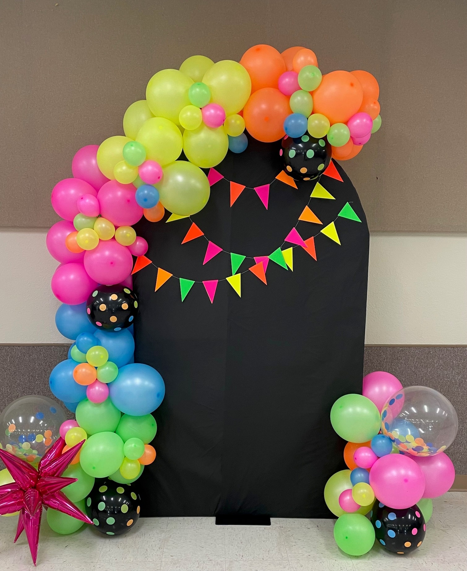 Neon balloon arch with black backdrop and bunting